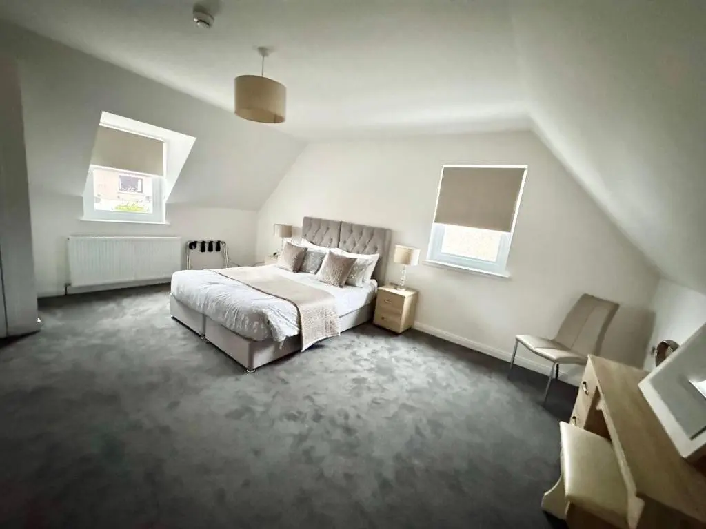 a white bedroom with a bed and a chair at Suites Holiday Home Inverness in Inverness