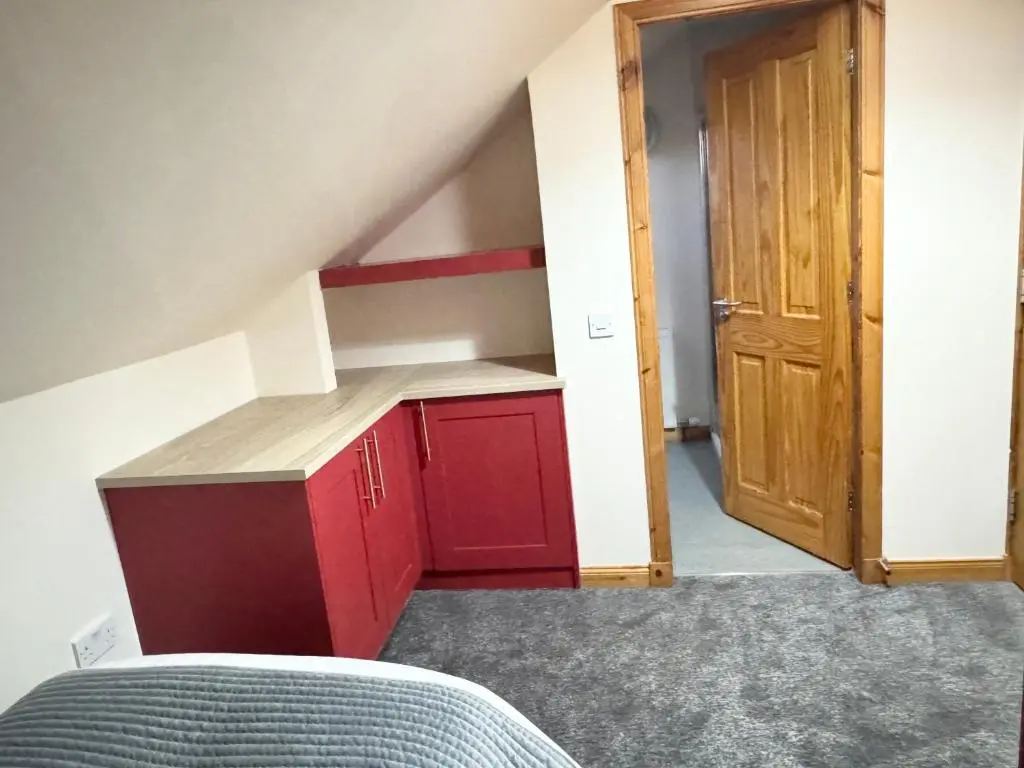 a small kitchen with red cabinets and a door at Suites Holiday Home Inverness in Inverness