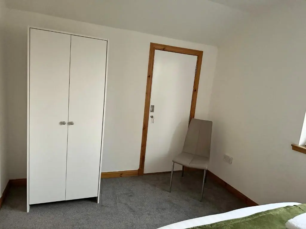 a bedroom with a white cabinet and a chair at Suites Holiday Home Inverness in Inverness