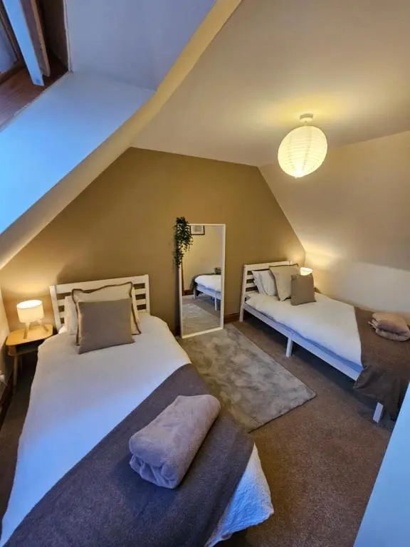 a attic bedroom with two beds and a mirror at The Saddlery Inverness in Dalneigh