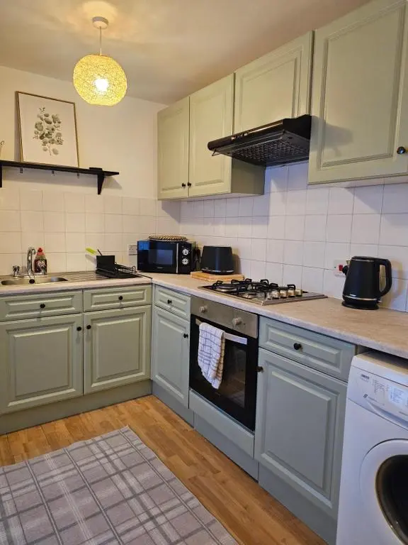 a kitchen with white cabinets and a stove top oven at The Saddlery Inverness in Dalneigh
