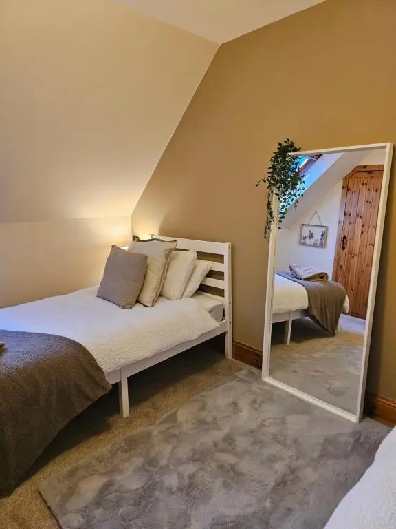 a bedroom with a bed and a mirror at The Saddlery Inverness in Dalneigh