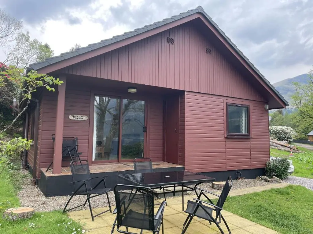 a house with a table and chairs in front of it at Mountain Thyme Lodge in Kilfinnan