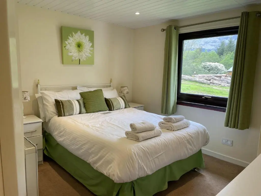 a bedroom with a bed with towels on it at Mountain Thyme Lodge in Kilfinnan