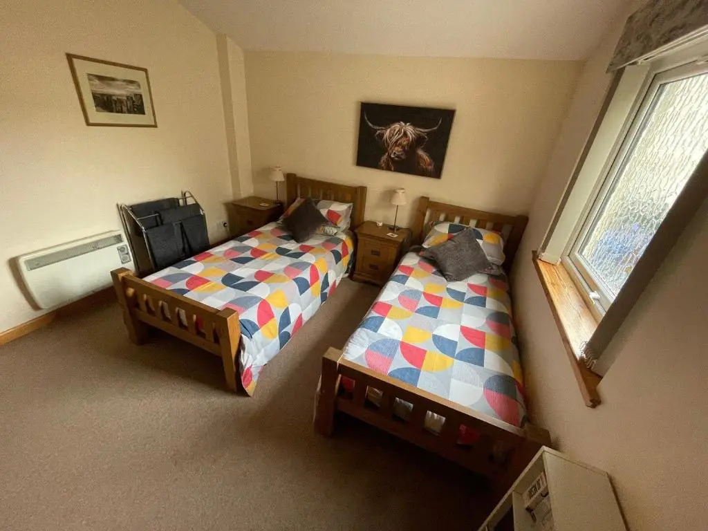 a bedroom with two beds and a window at Hopeman Cottages in Hopeman