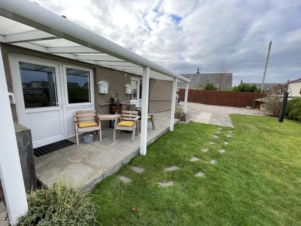 a patio with a table and chairs in a yard at Hopeman Cottages in Hopeman
