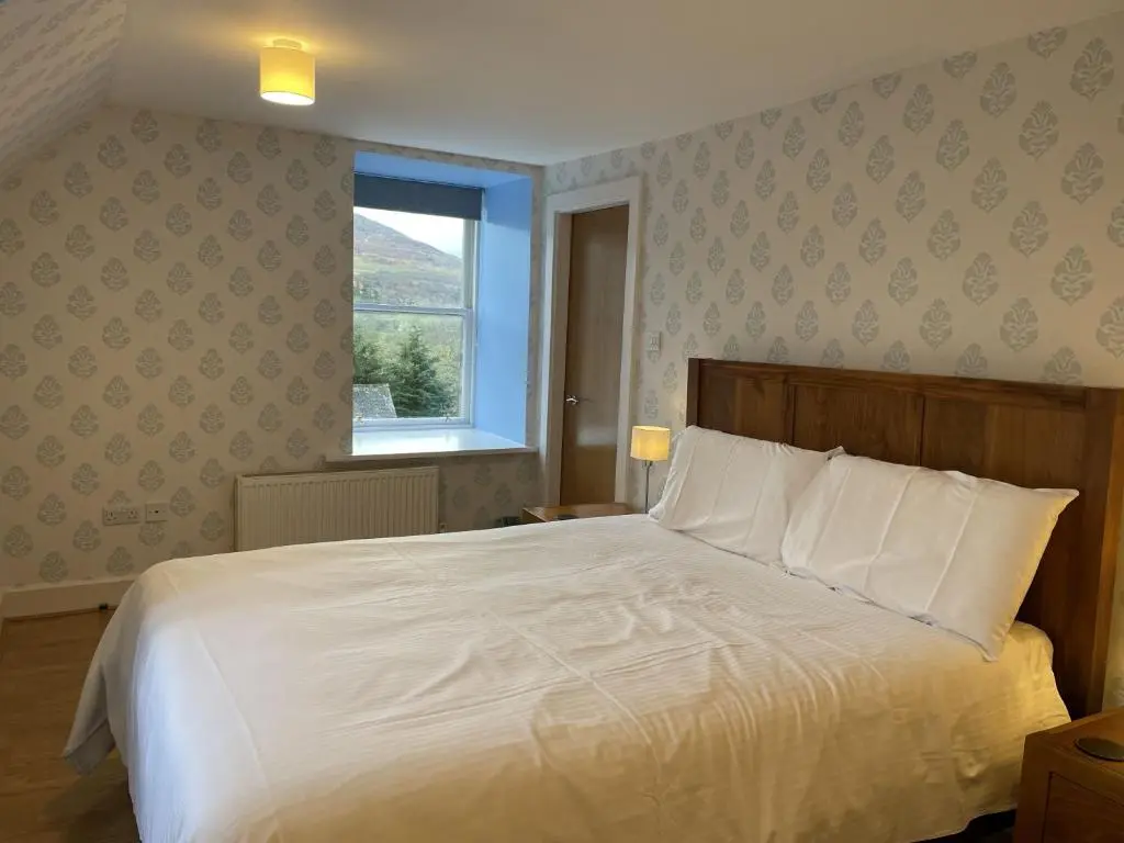 a bedroom with a large white bed and a window at Moat House 6 in Fort Augustus
