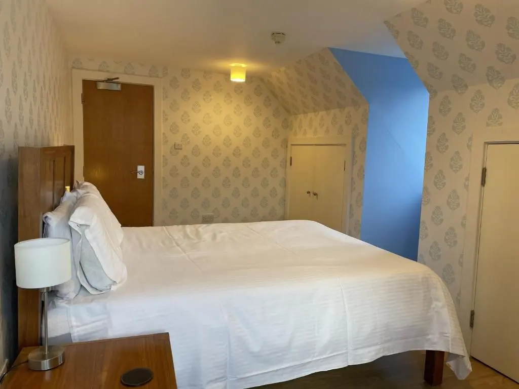 a bedroom with a white bed and a blue wall at Moat House 6 in Fort Augustus
