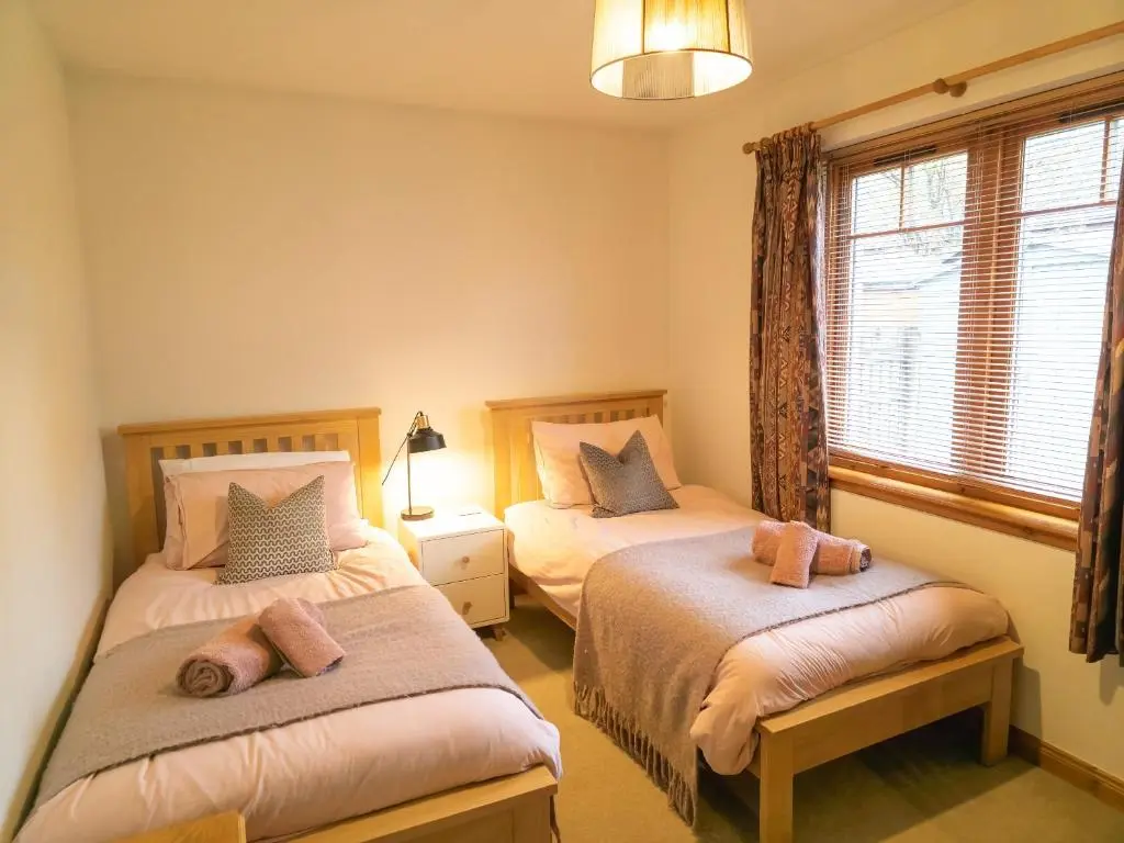 a bedroom with two beds and a window at Casa Amor in Aviemore