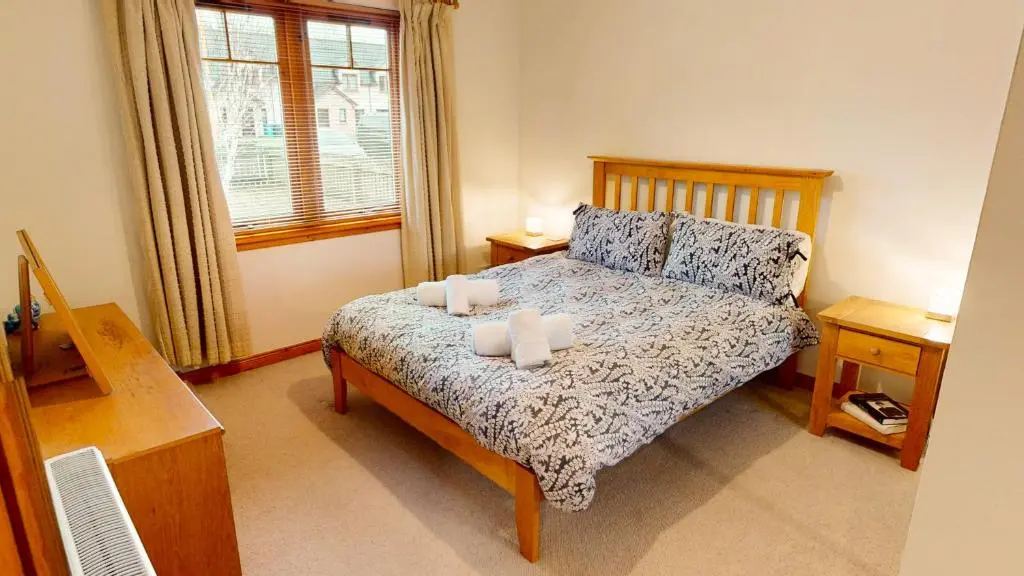a bedroom with a bed with two pillows and a window at Casa Amor in Aviemore