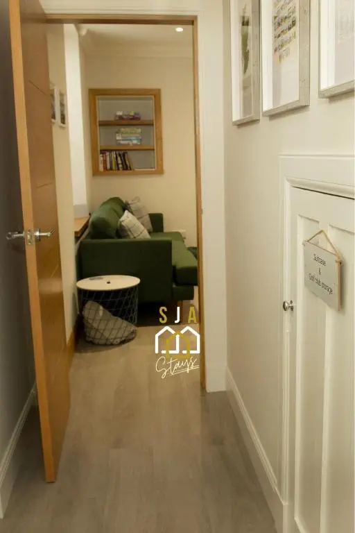 a hallway with a green couch in a living room at Beachside Cottage - SJA Stays - Modern 3 Bedroom House in Cullen