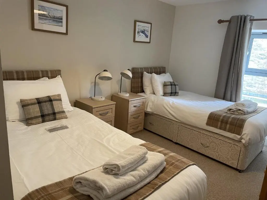 a bedroom with two beds and a window at Raven Wing 11 - Kintail Apartment in Fort Augustus