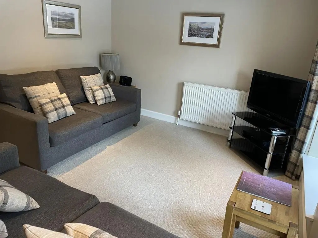 a living room with a couch and a television at Raven Wing 11 - Kintail Apartment in Fort Augustus