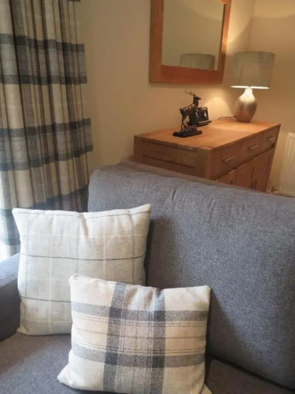 a living room with a couch and a mirror at Raven Wing 11 - Kintail Apartment in Fort Augustus