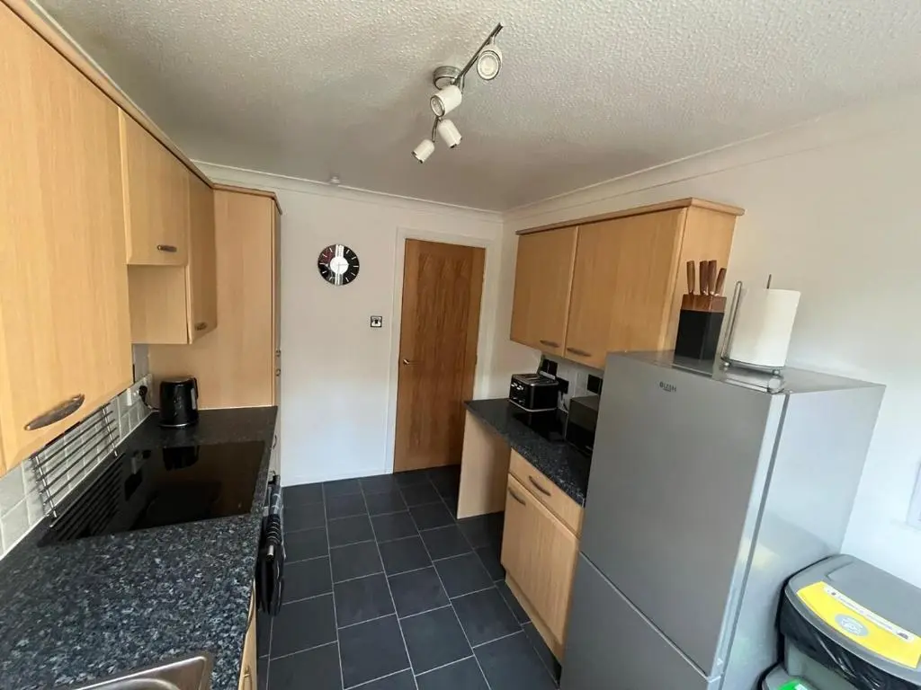 a kitchen with a refrigerator and wooden cabinets at 26 Two bedroom apt with private garden in Culloden