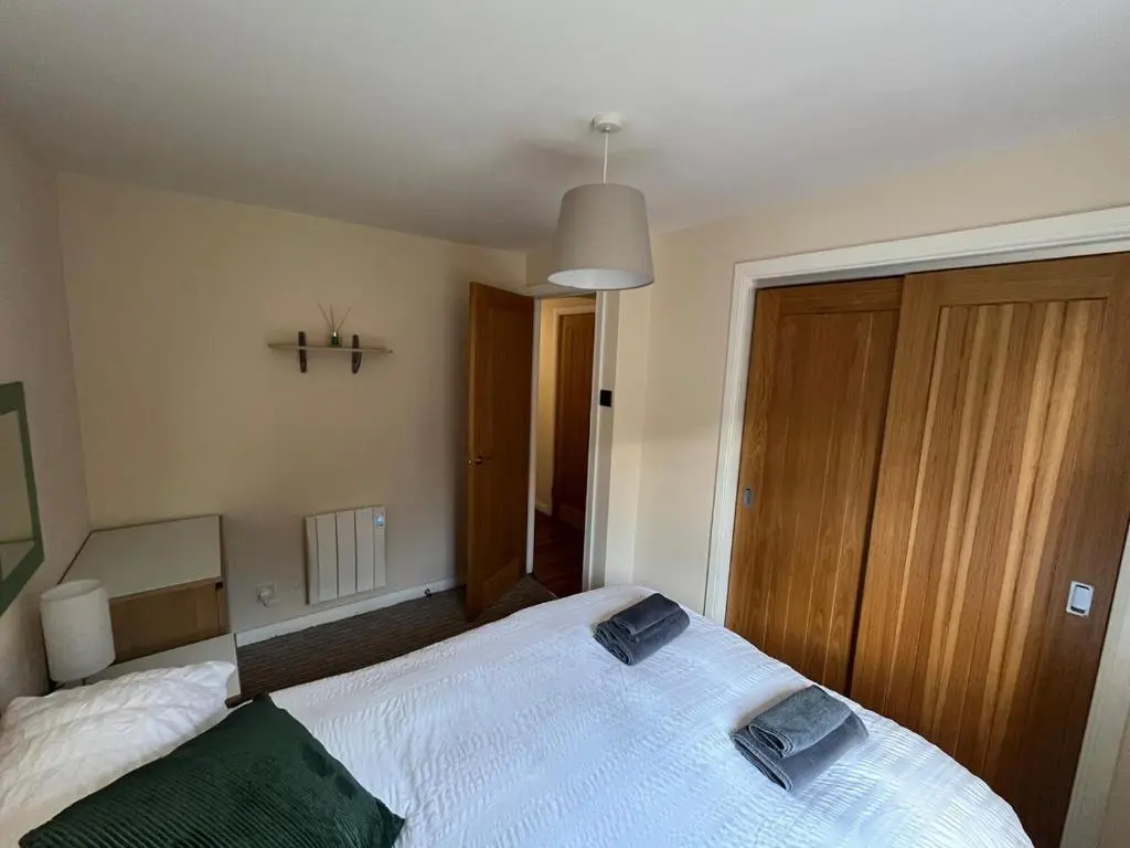 a bedroom with a white bed and a wooden door at 26 Two bedroom apt with private garden in Culloden