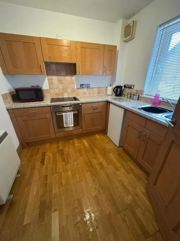 a kitchen with wooden cabinets and a wooden floor at Church Street Apartment in Inverness