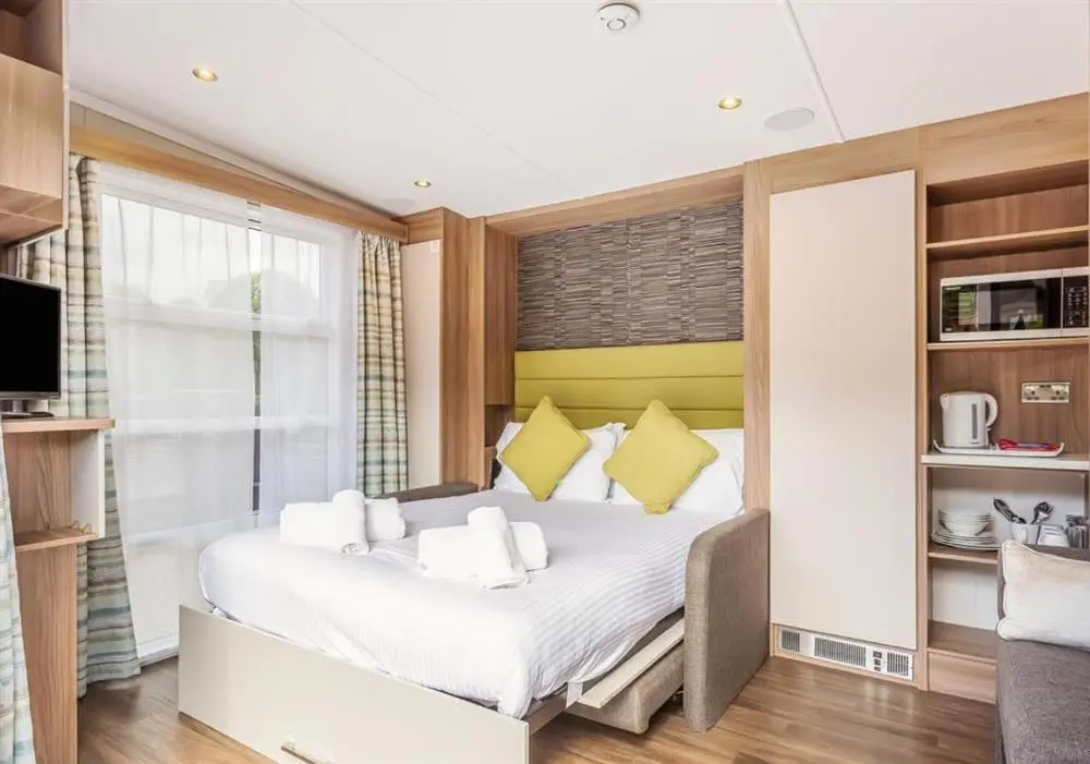 a bedroom with a large white bed with yellow pillows at Loch Ness Highland Resort in Fort Augustus