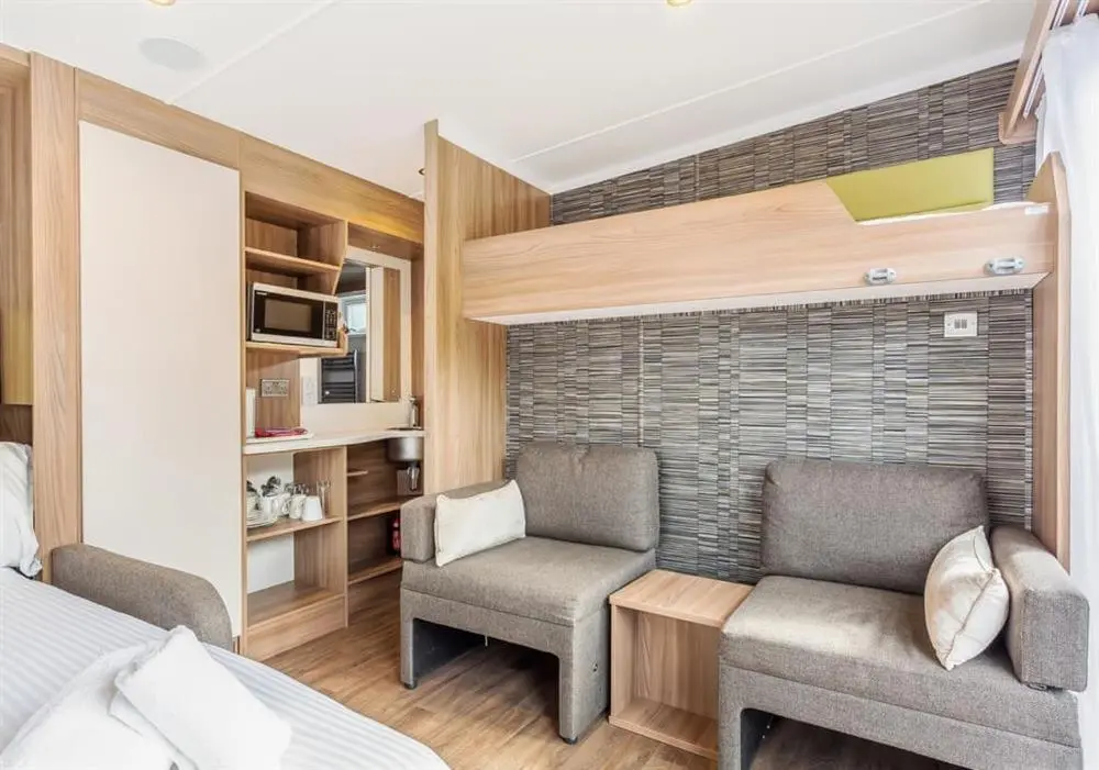 a bedroom with a bed and two chairs and a tv at Loch Ness Highland Resort in Fort Augustus