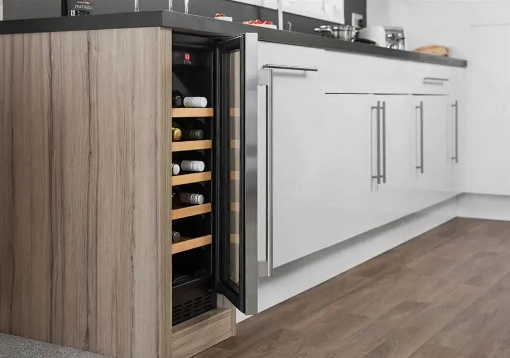 a kitchen with white and wooden cabinets with wine racks at Loch Ness Highland Resort in Fort Augustus
