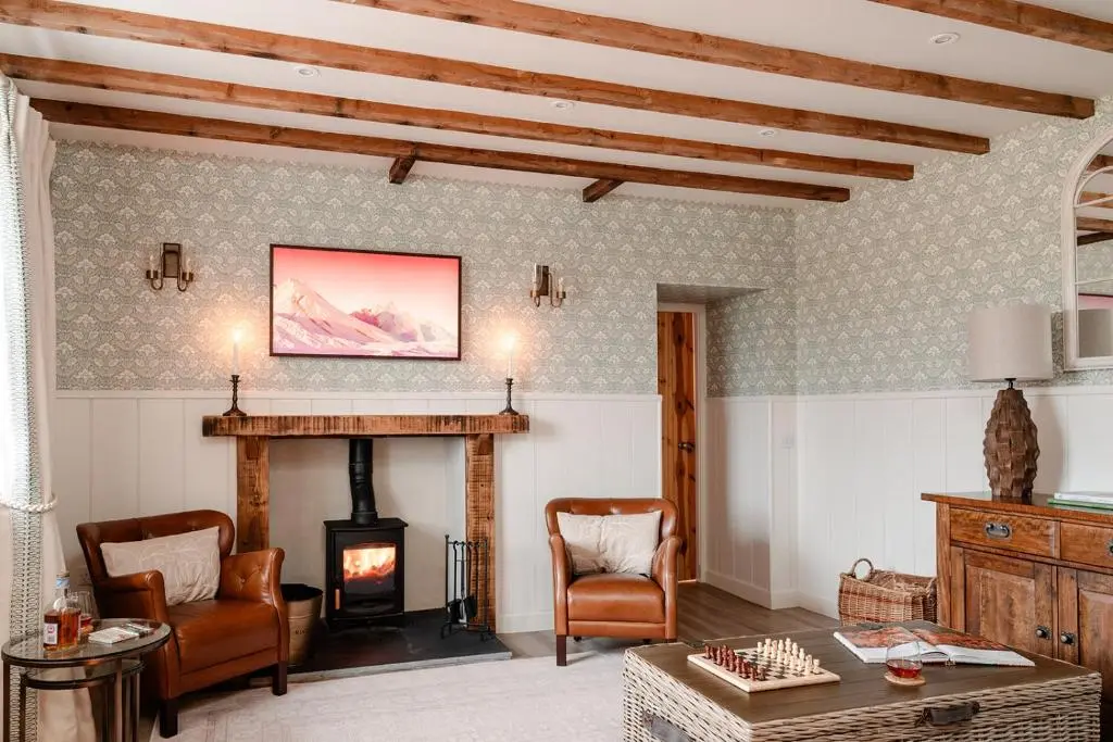 a living room with a fireplace and a table and chairs at Garradh Cottage - Seasgair Lodges in Kincraig