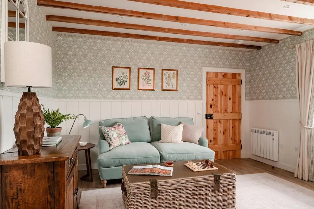 a living room with a blue couch and a table at Garradh Cottage - Seasgair Lodges in Kincraig