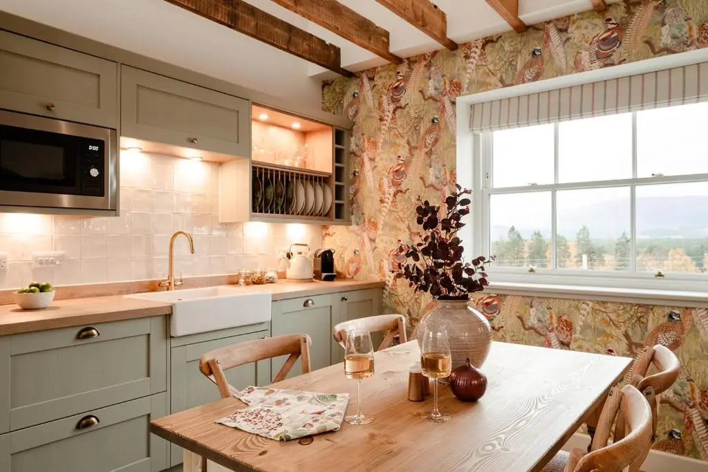 a kitchen with a table with chairs and a vase with flowers at Garradh Cottage - Seasgair Lodges in Kincraig