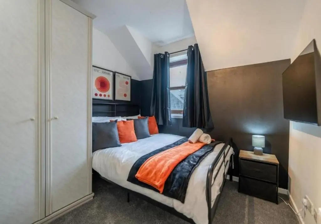 a bedroom with a bed with orange and blue pillows at Bright & Spacious 2BR Fraserburgh for Work & Family Stays in Fraserburgh