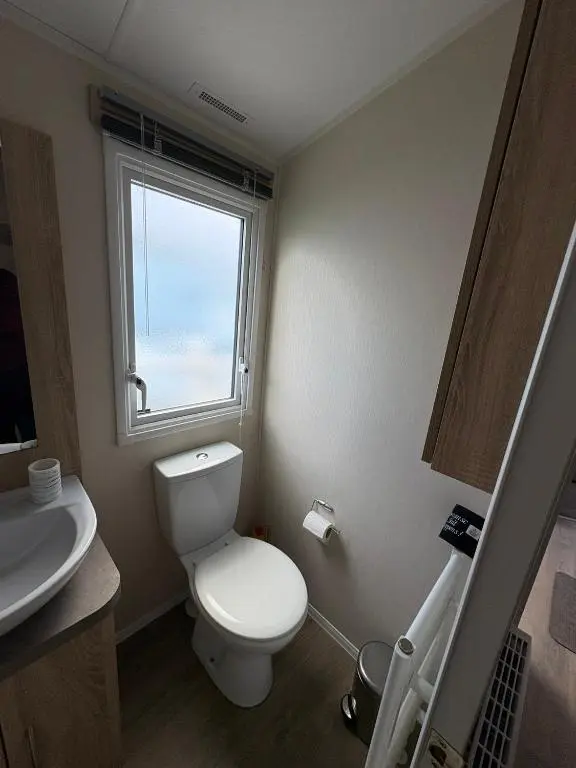 a bathroom with a toilet and a sink and a window at Pebble Cove 74 in Lossiemouth