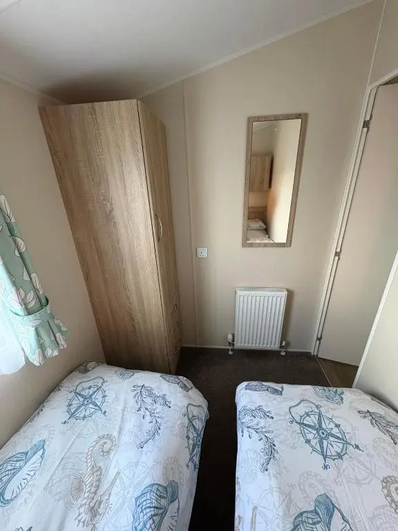 a small bedroom with two beds and a mirror at Pebble Cove 74 in Lossiemouth