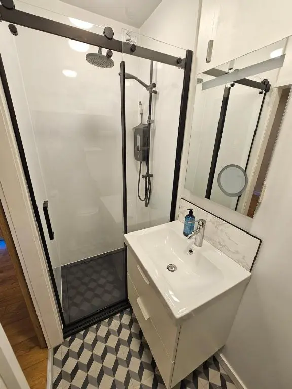 a bathroom with a shower and a white sink at Inverness City Centre Studio Flat in Inverness