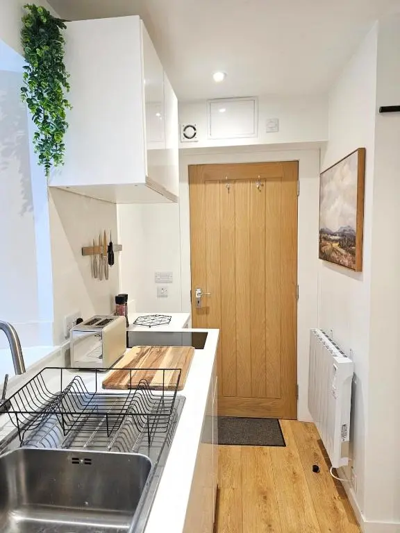 a kitchen with a sink and a wooden door at Inverness City Centre Studio Flat in Inverness