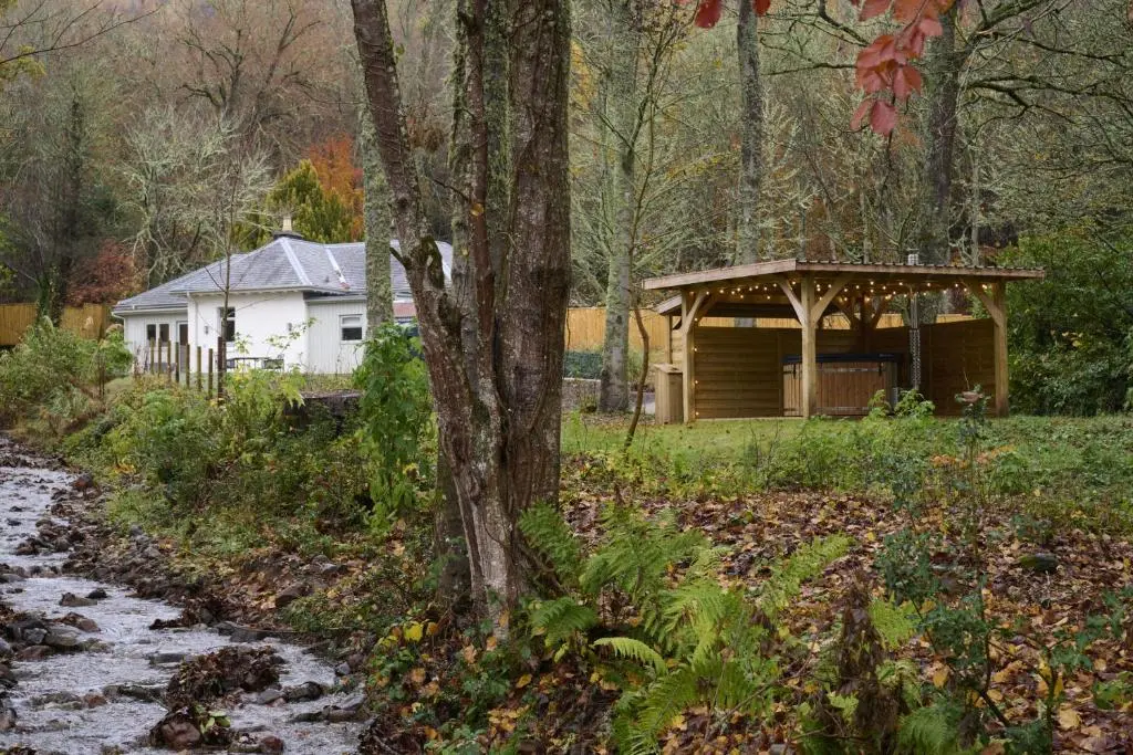 a cabin in the woods next to a tree at Church Cottage in Inverness