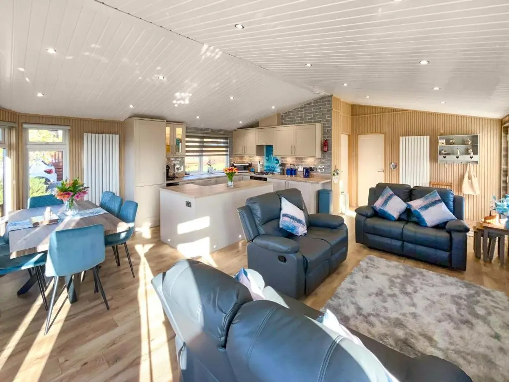 a living room with blue furniture and a kitchen at Haven Lodge - Uk50792 in Banchory
