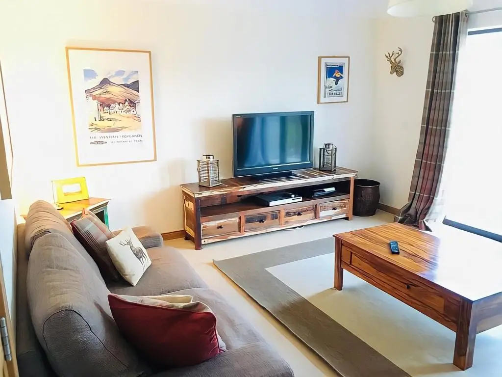 a living room with a couch and a flat screen tv at Carn Mhor Lodge in Aviemore