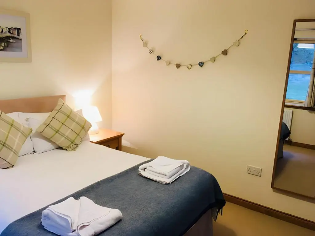 a bedroom with a bed with two towels on it at Carn Mhor Lodge in Aviemore