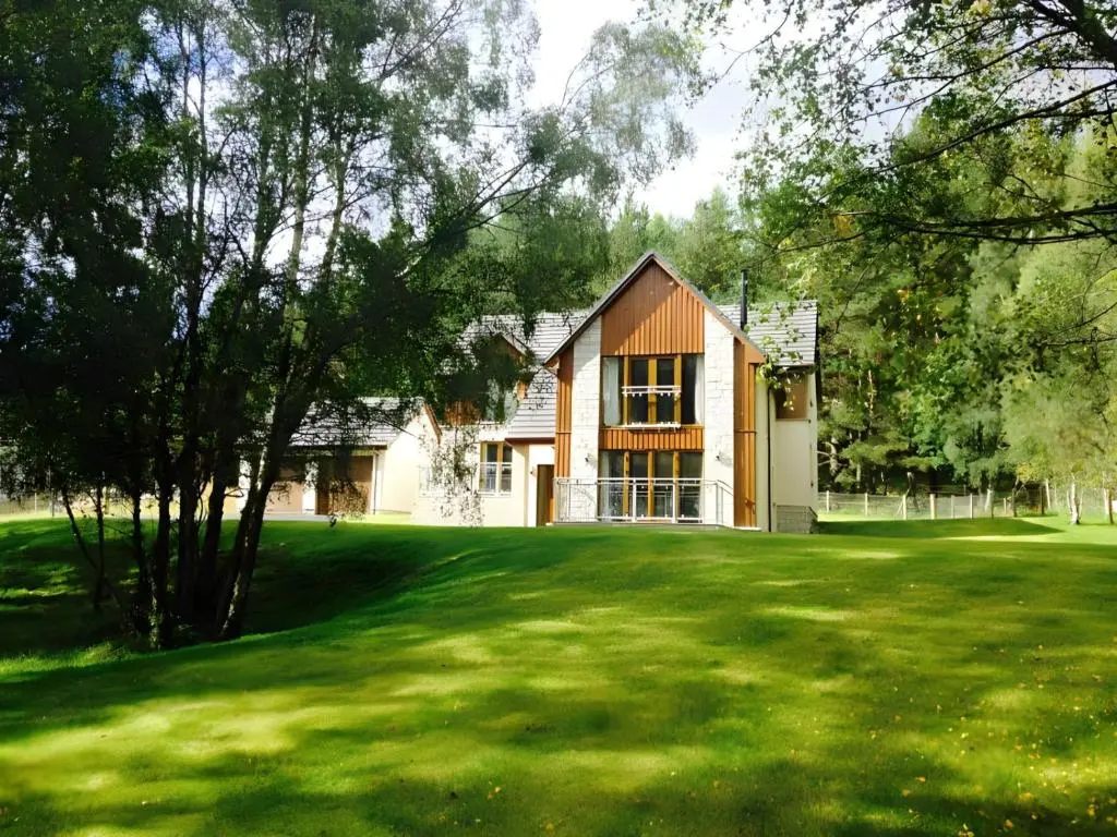 a house on a lawn with a large green yard at Carn Mhor Lodge in Aviemore