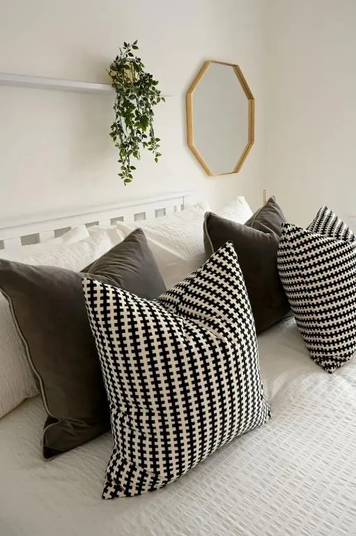 a pile of pillows on a bed with a mirror at High-Ness View in Inverness