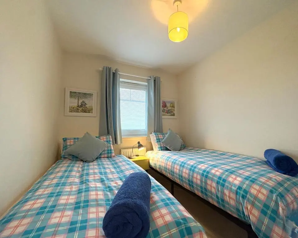 two twin beds in a room with a window at Primrose View House in Inshes