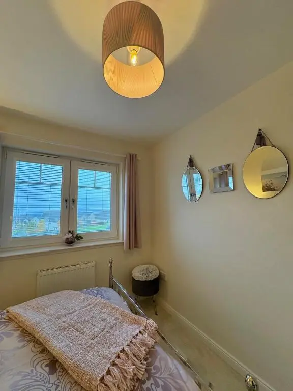 a bedroom with a bed and a chandelier at Primrose View House in Inshes