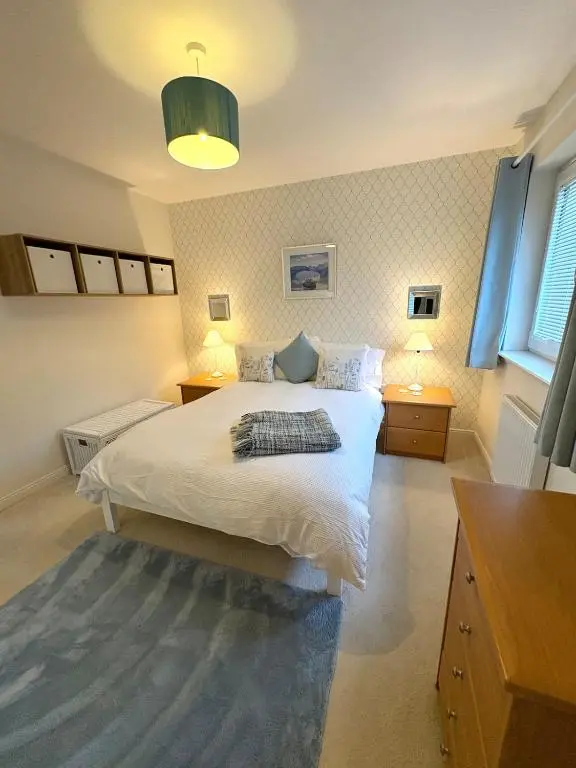 a bedroom with a large white bed with two lamps at Primrose View House in Inshes