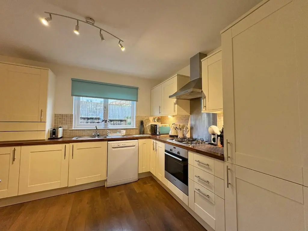 a large kitchen with white cabinets and a window at Primrose View House in Inshes