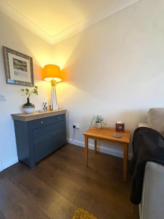 a room with a bed and a table with a lamp at Primrose View House in Inshes
