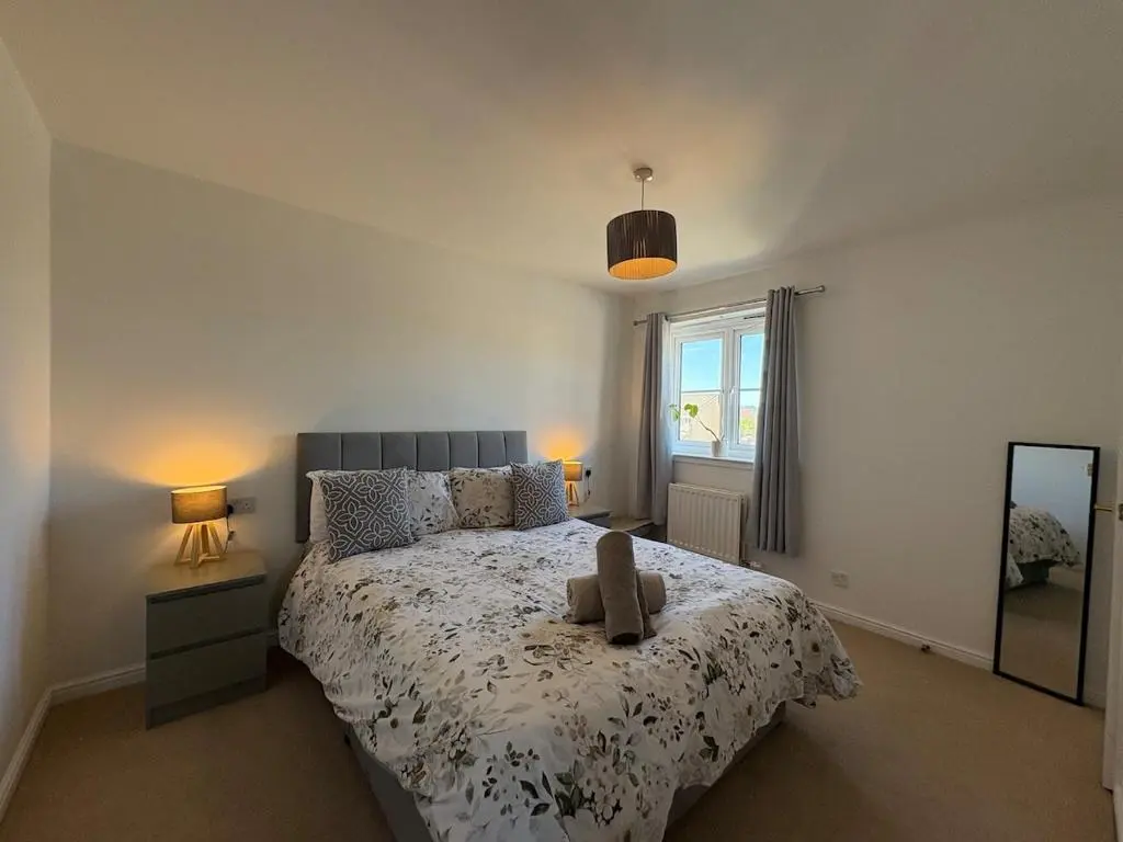 a bedroom with a bed and two lamps and a mirror at Peaceful Abode in Inshes