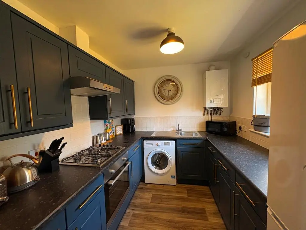 a kitchen with blue cabinets and a washing machine at Peaceful Abode in Inshes