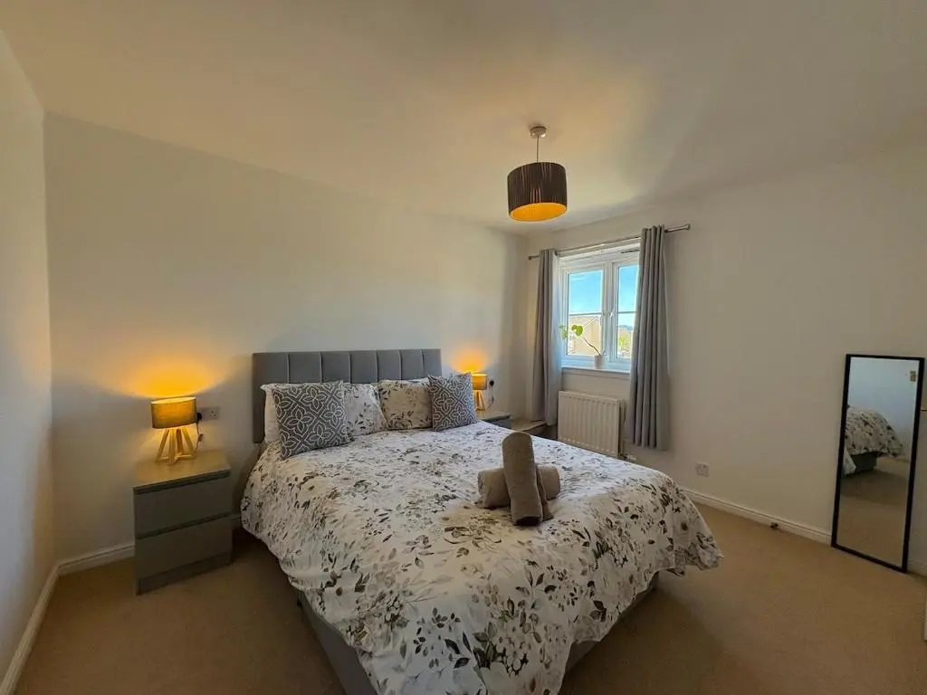 a bedroom with a bed and two lamps and a mirror at Peaceful Abode in Inshes