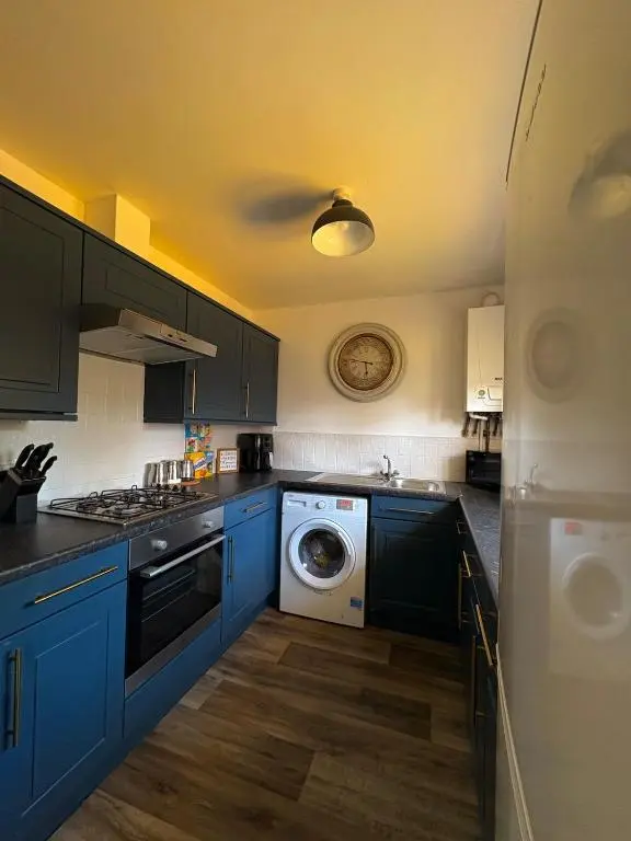a kitchen with blue cabinets and a washing machine at Peaceful Abode in Inshes