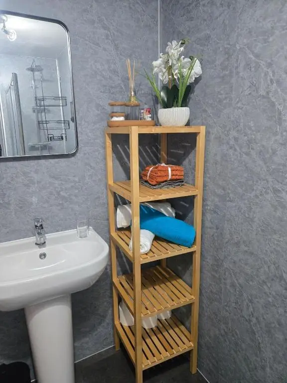a bathroom with a sink and a shelf with towels at The Highland Nook in South Kessock