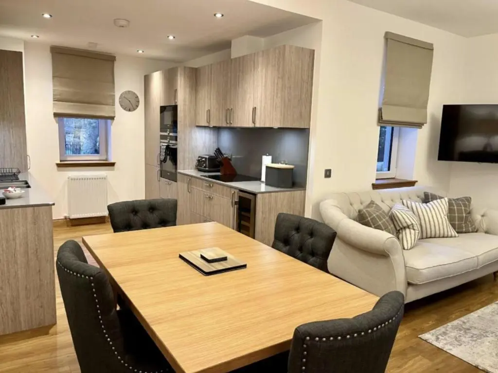 a kitchen and living room with a table and a couch at Royal Gardens Apartment 19 in Dornoch