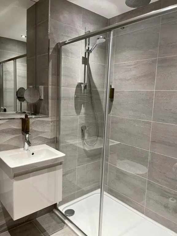 a bathroom with a shower with a sink and a toilet at Royal Gardens Apartment 19 in Dornoch